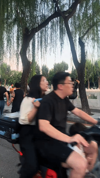 一名专业摄影师正在街头给女模特拍摄写真照。
这时，一位骑车路过这里的大爷看到有美