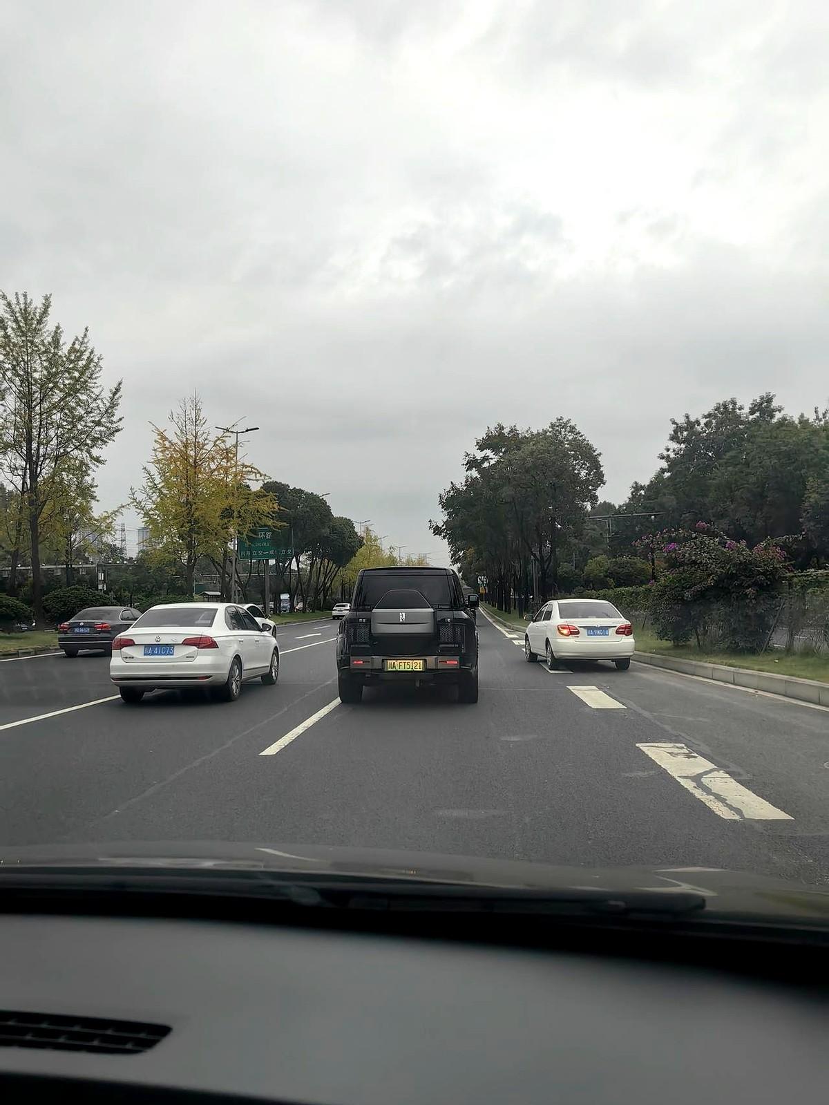 即使温度只有15度，一位穿着白背心、红短裤、围着白毛巾的女士仍在繁忙的三环辅道上