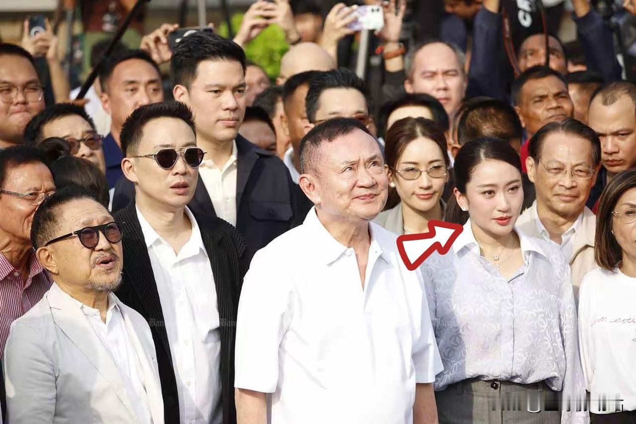 他信旁边站着年轻女子是他的小女儿佩通坦·西那瓦，也是前任泰国总理。

主要因20