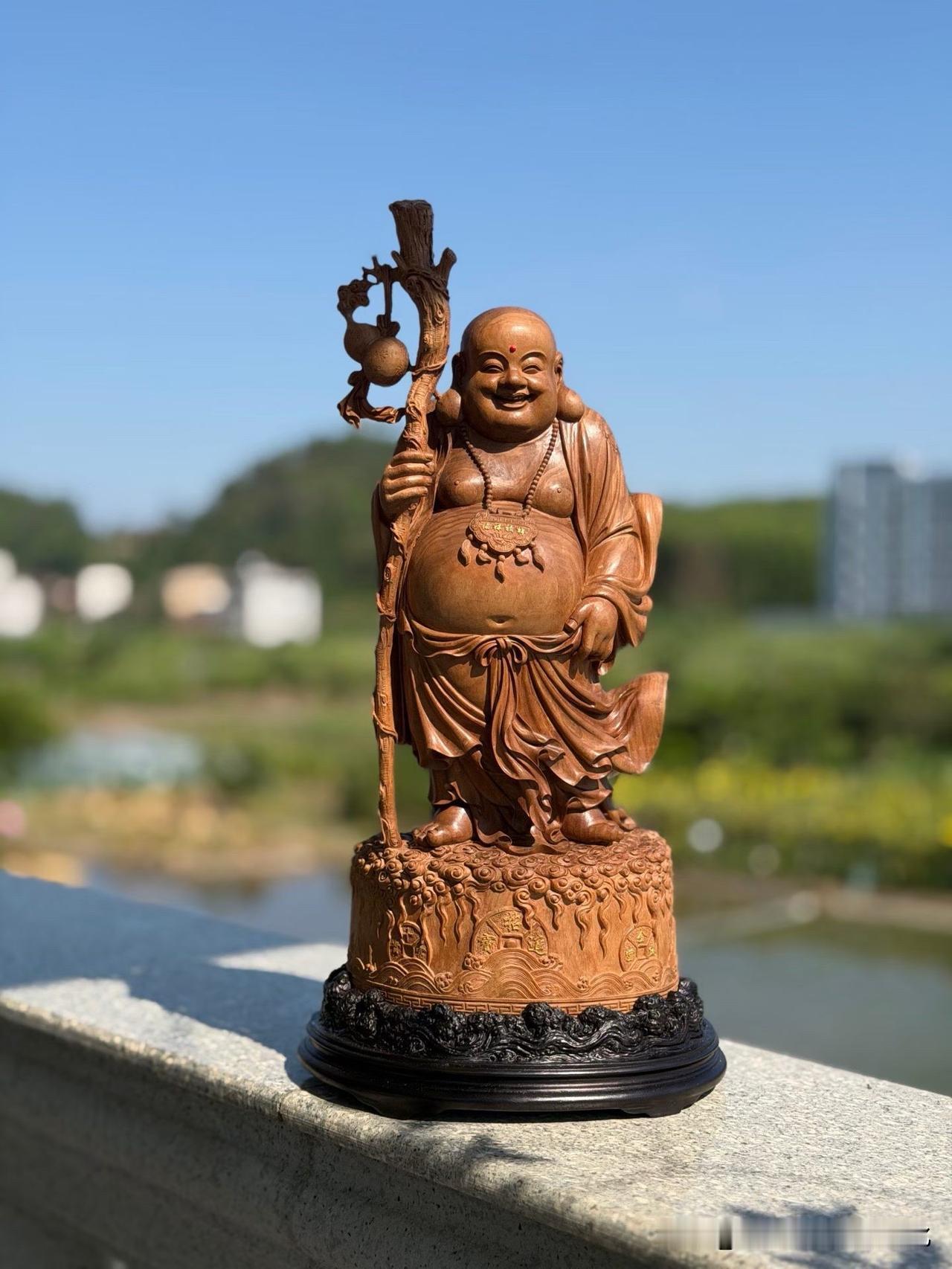 木色深沉，檀香温润，弥勒含笑而坐。

圆润的体态、舒展的眉眼，在清刀流转之间显出