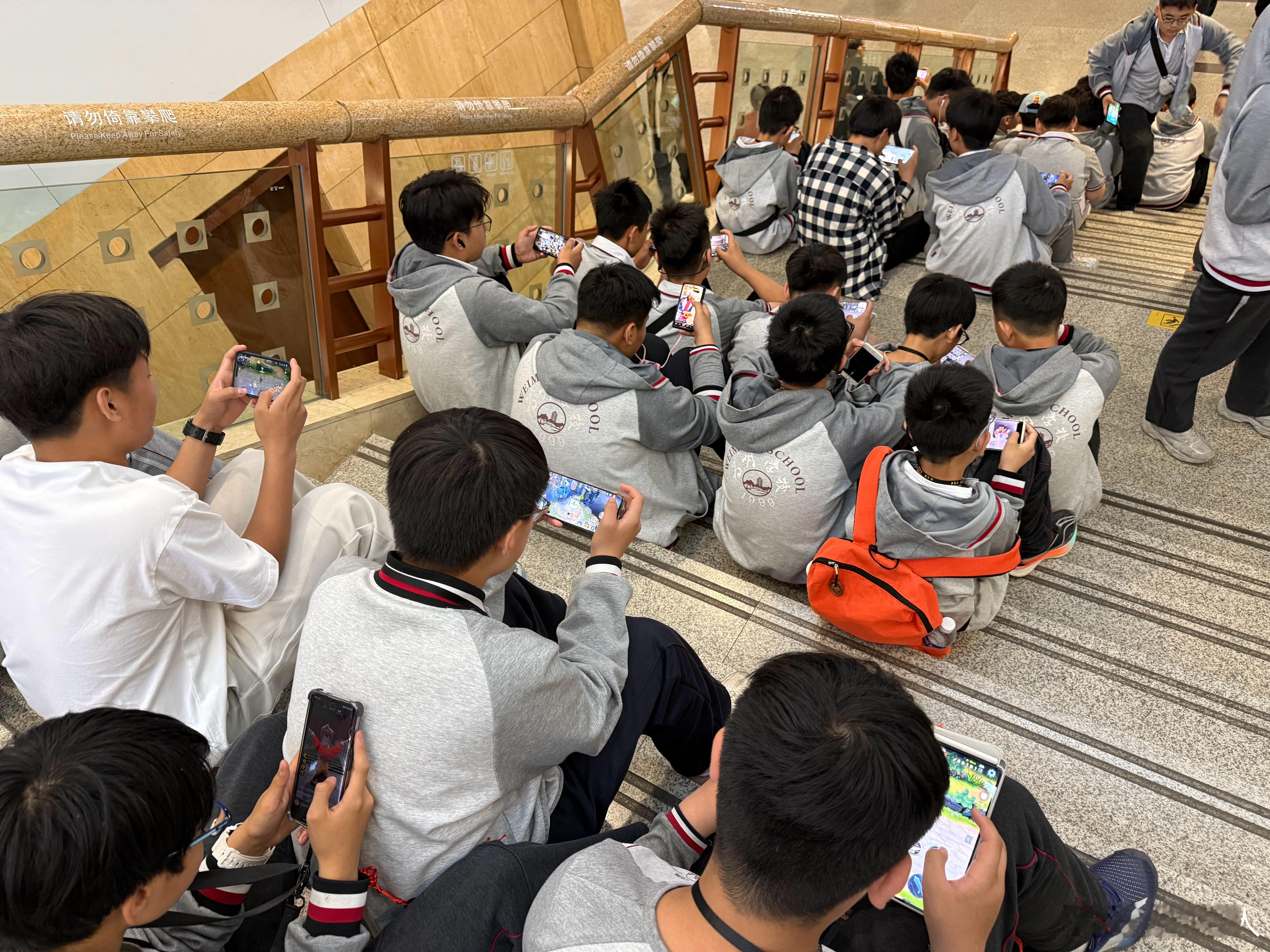 山西省博某中学参观，所有学生统一坐在博物馆中间楼梯上打游戏，壮观