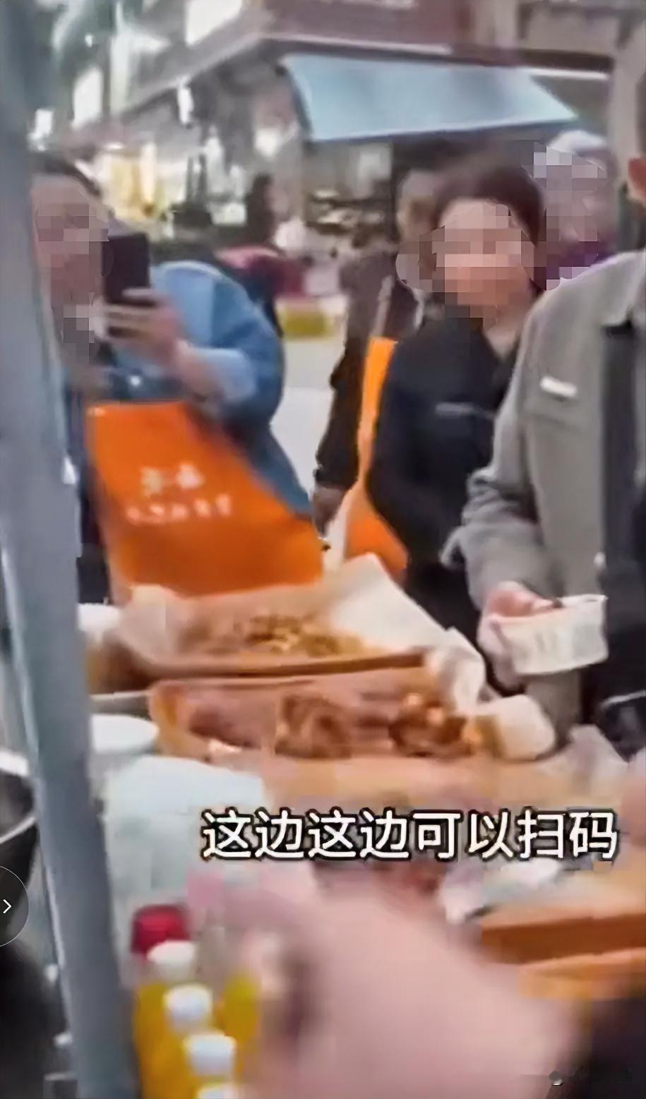 好不好吃，好吃
麻烦你扫一下码，不好意思，今天没带钱。
一大妈在街边品尝小吃摊位