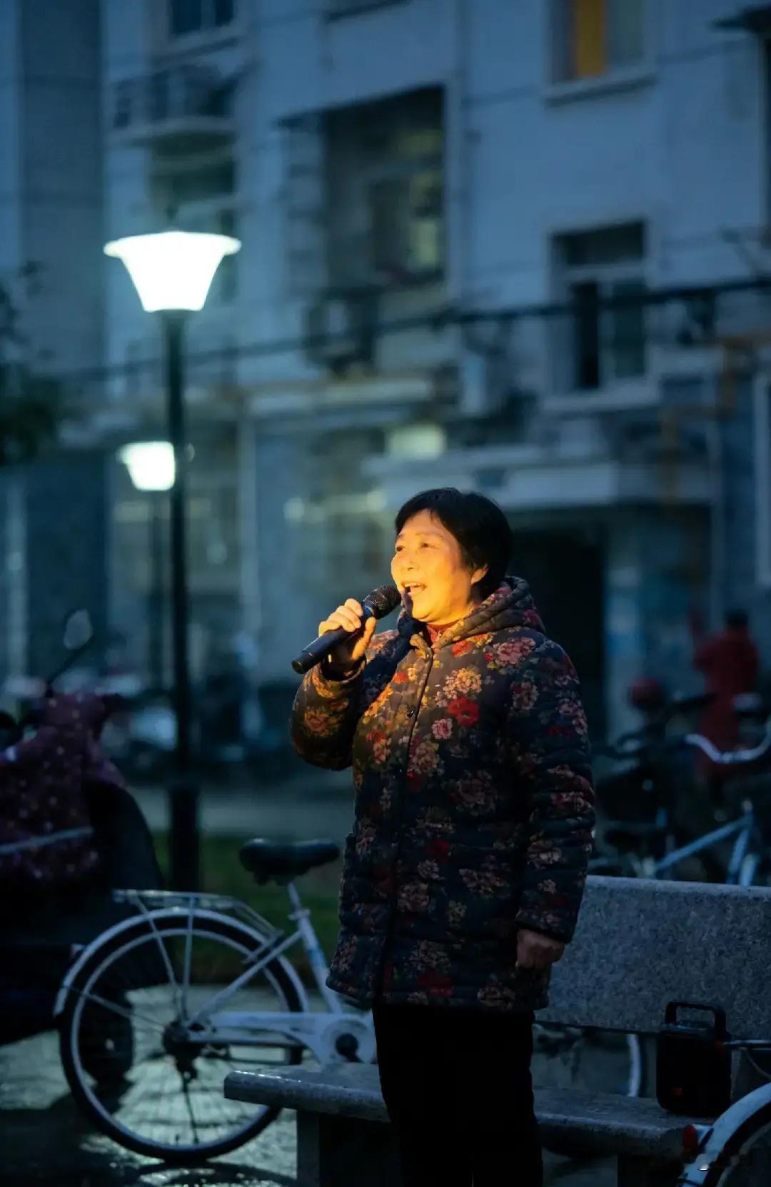 青山区梧桐苑的大妈每天六点准时开麦唱《夕阳红》，便携音箱音量开到顶，整栋楼跟着震