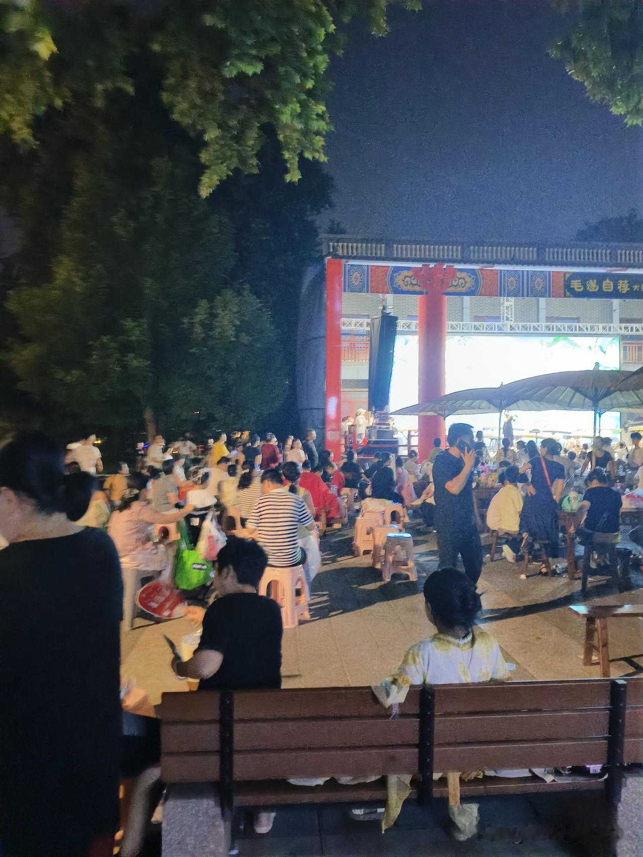 夜晚热闹的街头，大家围坐一起享受美食。黄昏下的小吃街 逛街城市夜景