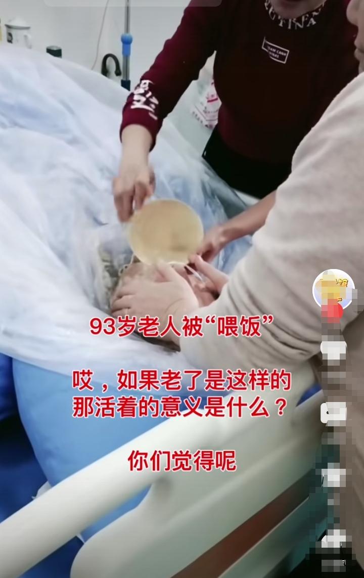 93岁的老人在病床上被喂饭，看上去真的好可怜！只见男子双手握按住老人的头，不让老