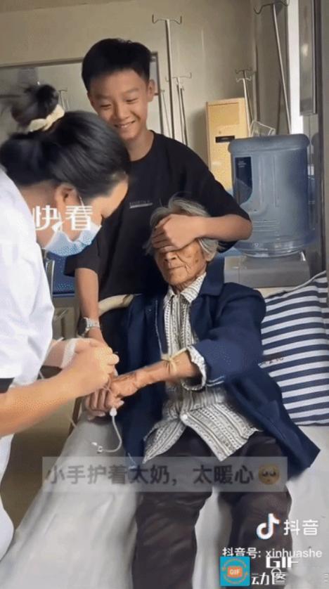 湖北，重孙陪86岁太奶去看病，当看到护士要扎太奶手时，担心太奶害怕打针，一把捂住