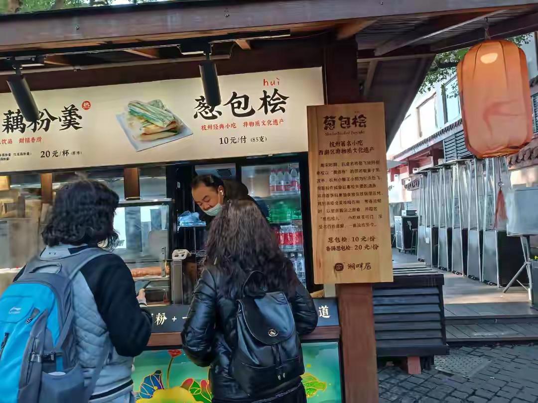 杭州有一款薄饼非常有名气，在西湖很多风景区都有售卖。

当你走入苏堤入口处，马上