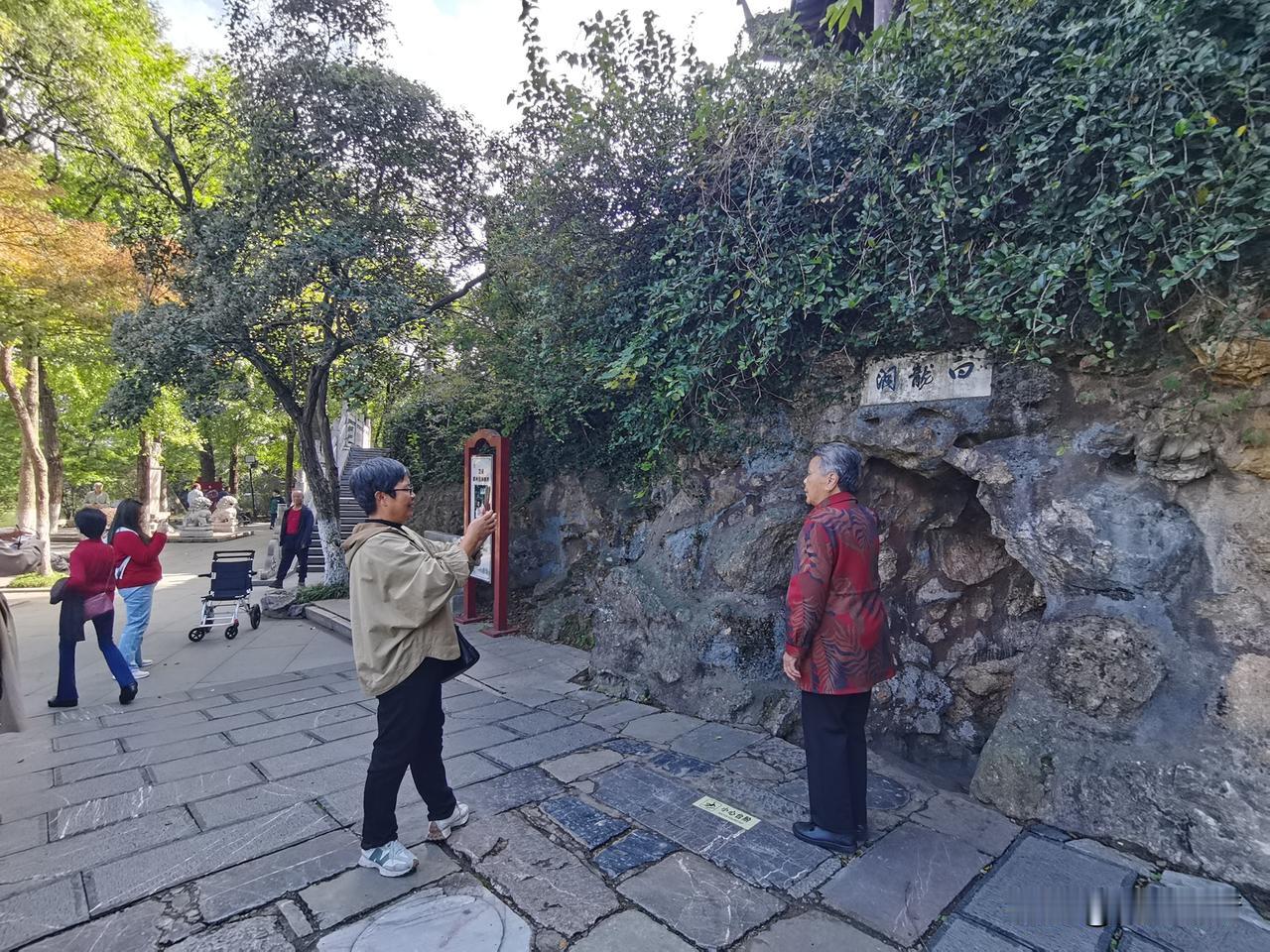 晒图笔记大赛寻迹白龙洞，山石藏旧韵。林间树荫漫落，子女举着镜头，定格长辈与古洞同