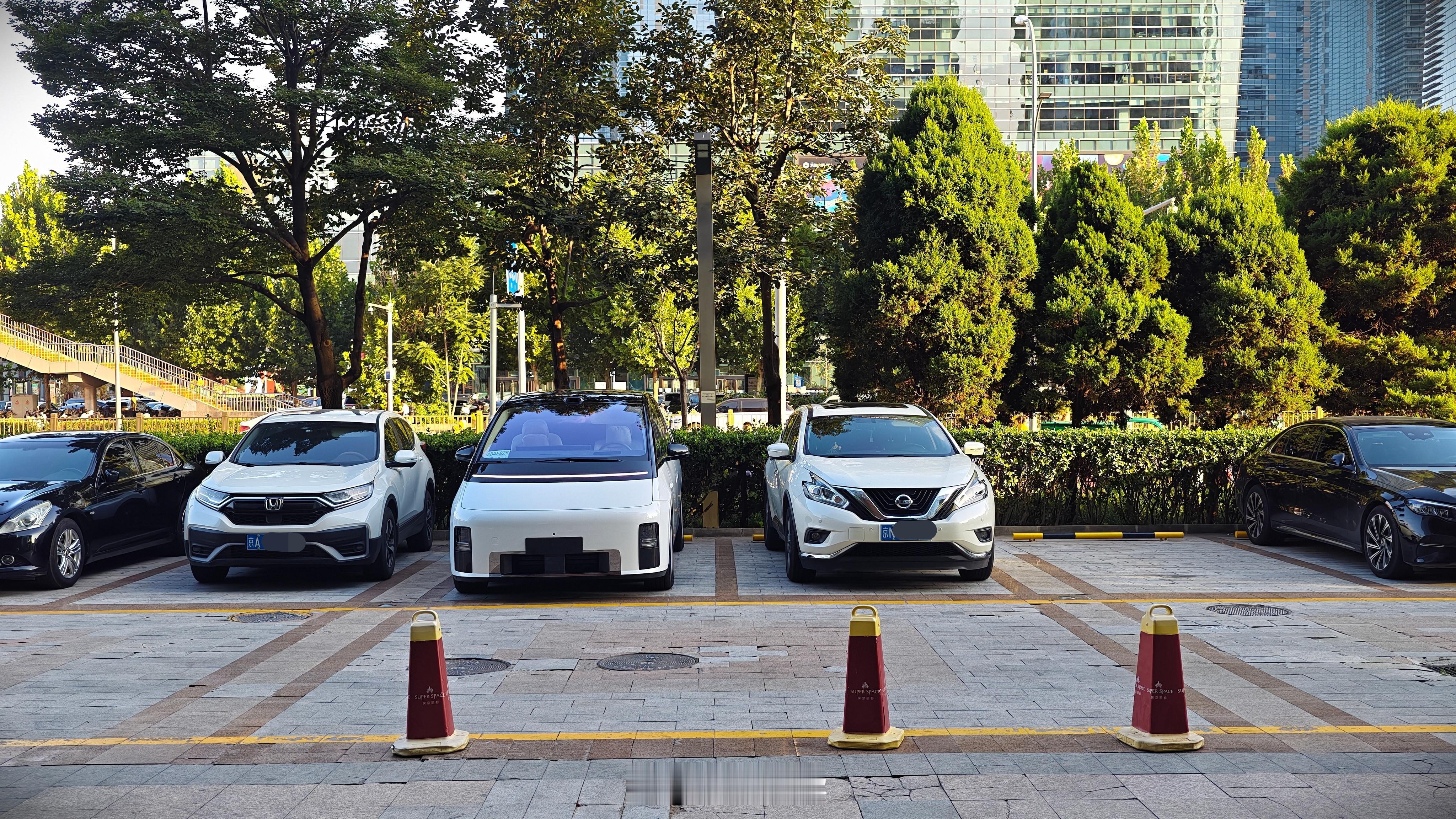 这个停车场真不错，每两个车位两边都各有一个挺宽的空白区域。大家也都把车靠向那一侧