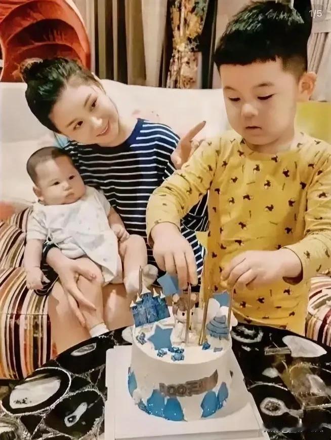 李小萌手抱着二儿子眼睛含情脉脉的看着大儿子，尽显满满的母爱，满脸笑容的看着大宝贝