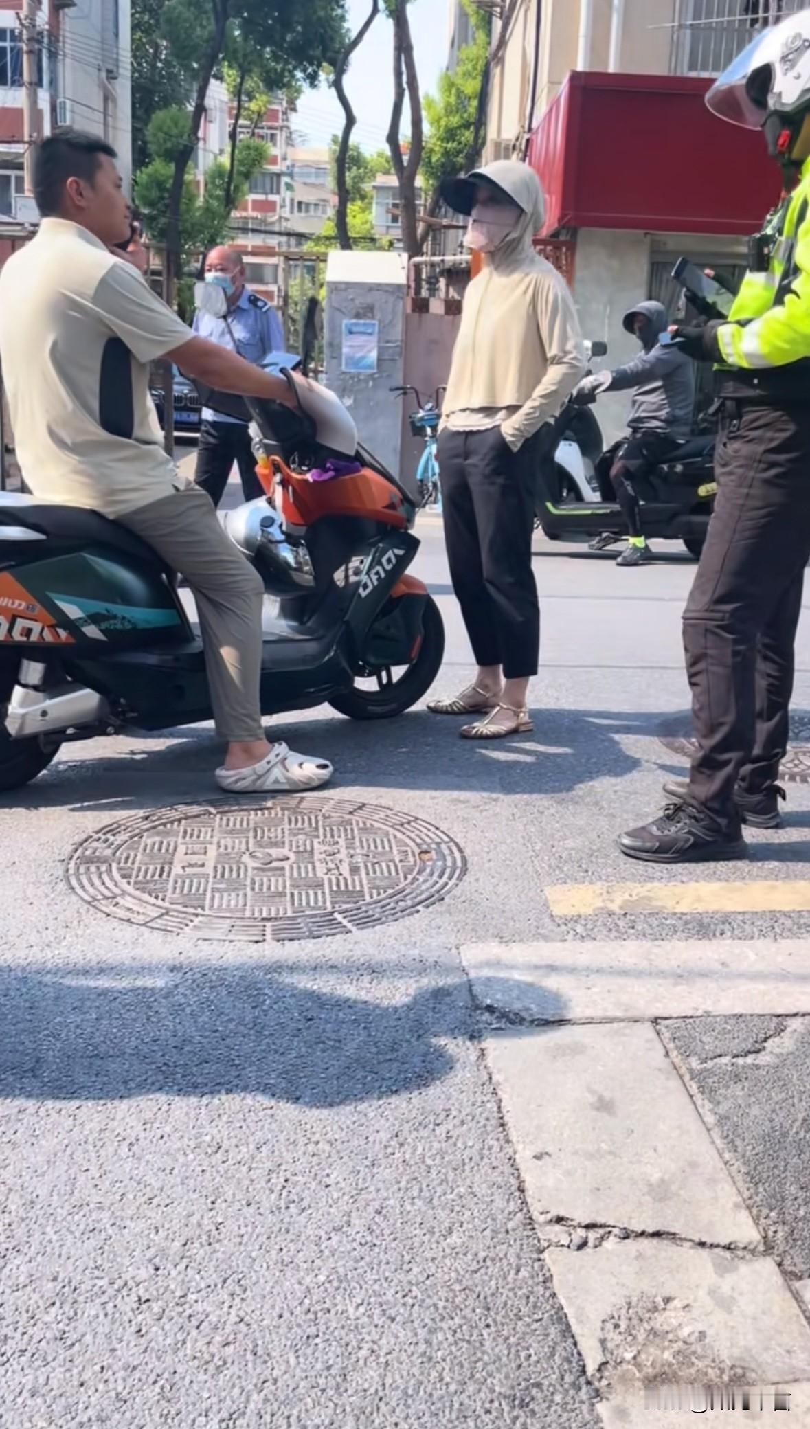 双手插兜、头戴防晒帽和口罩，不知道的还以为她很帅，因为发生事故，她拦住男车主不让