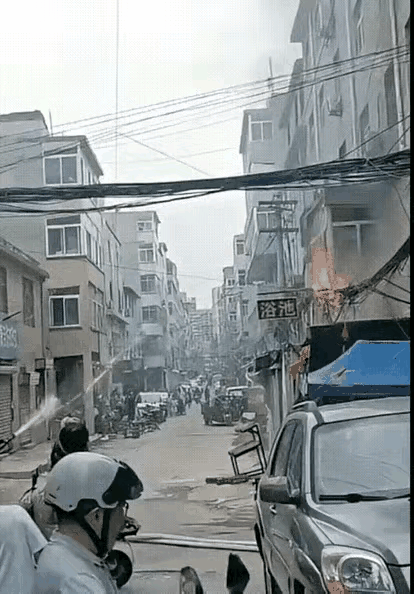 浴池外面的电线起火了，打过119后消防战士火速赶来，他们架起水枪点射灭火，有围观