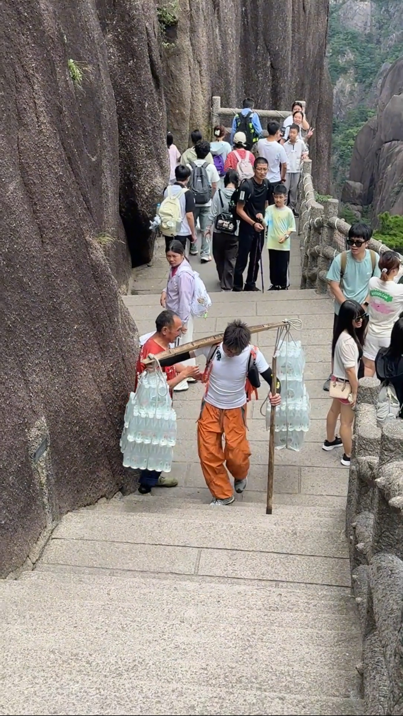 90后小伙爬黄山途中，遇挑山工休息，主动扛起扁担替师傅挑一程。路过的游客：你真善