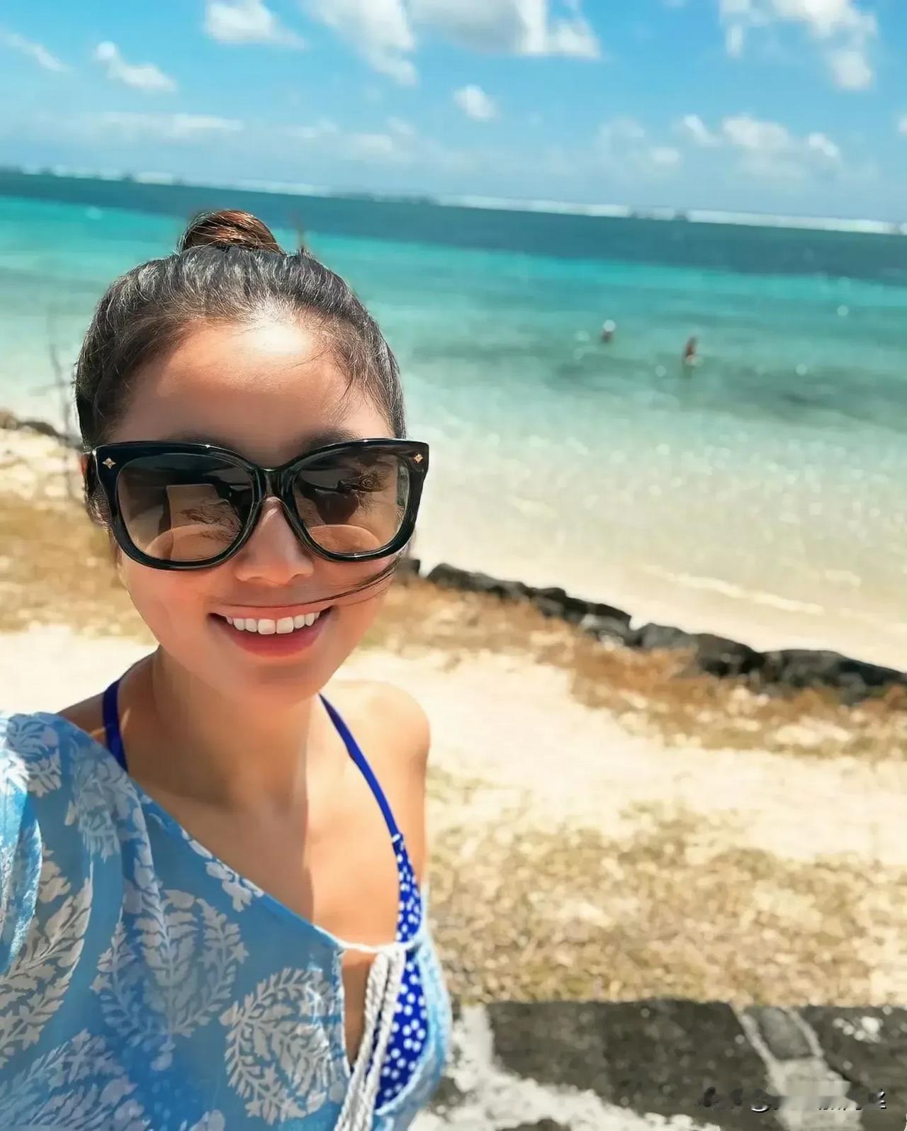 林心如最新沙滩度假美照曝光，她身着泳衣，头戴遮阳草帽，展现出优雅时尚的魅力。肌肤