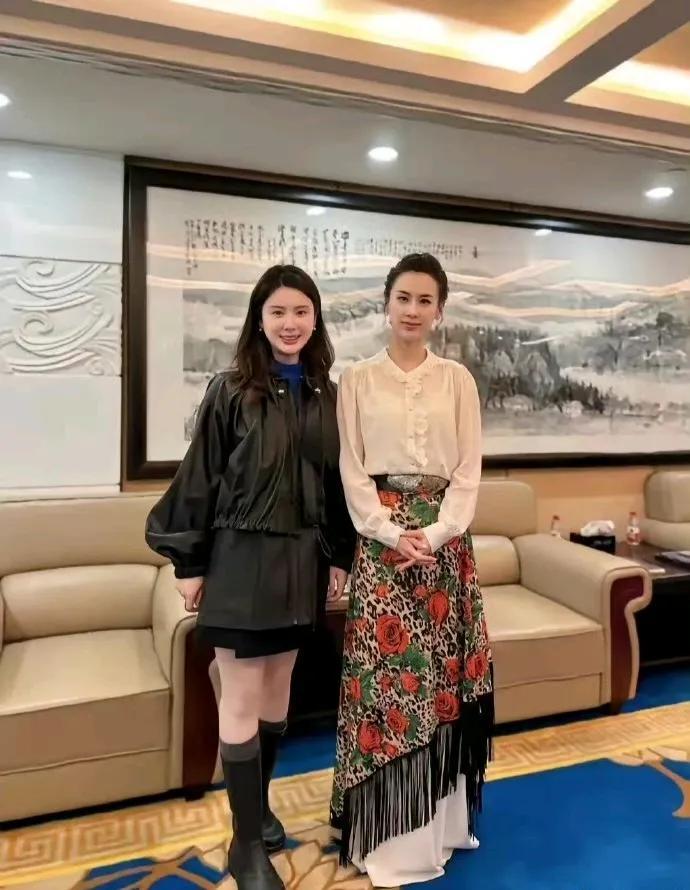 照片中的两位小姐姐真是一个比一个美啊。右边的黄圣依白色的衬衫搭配上印花红色长裙，