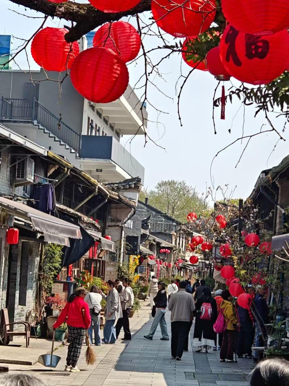 春日生活打卡季枝头的红灯笼映着青瓦白墙，老街的石板路上人来人往。风里裹着淡淡的烟