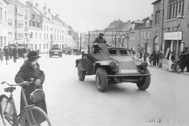 1940 年 4 月 12 日，一名丹麦妇女看着一辆德国Sd.Kfz. 223轻