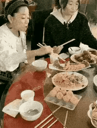 两位朋友在餐桌前愉快地吃饭。
这是吃什么饭局，可能是吃喜事的酒席，这个妇女太没有