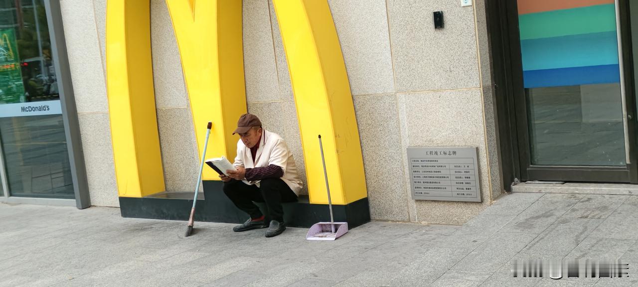 下雨了，一位保洁避在商场雨棚下开卷阅读
还不到下班的时候，因为天气阴冷，就提前回