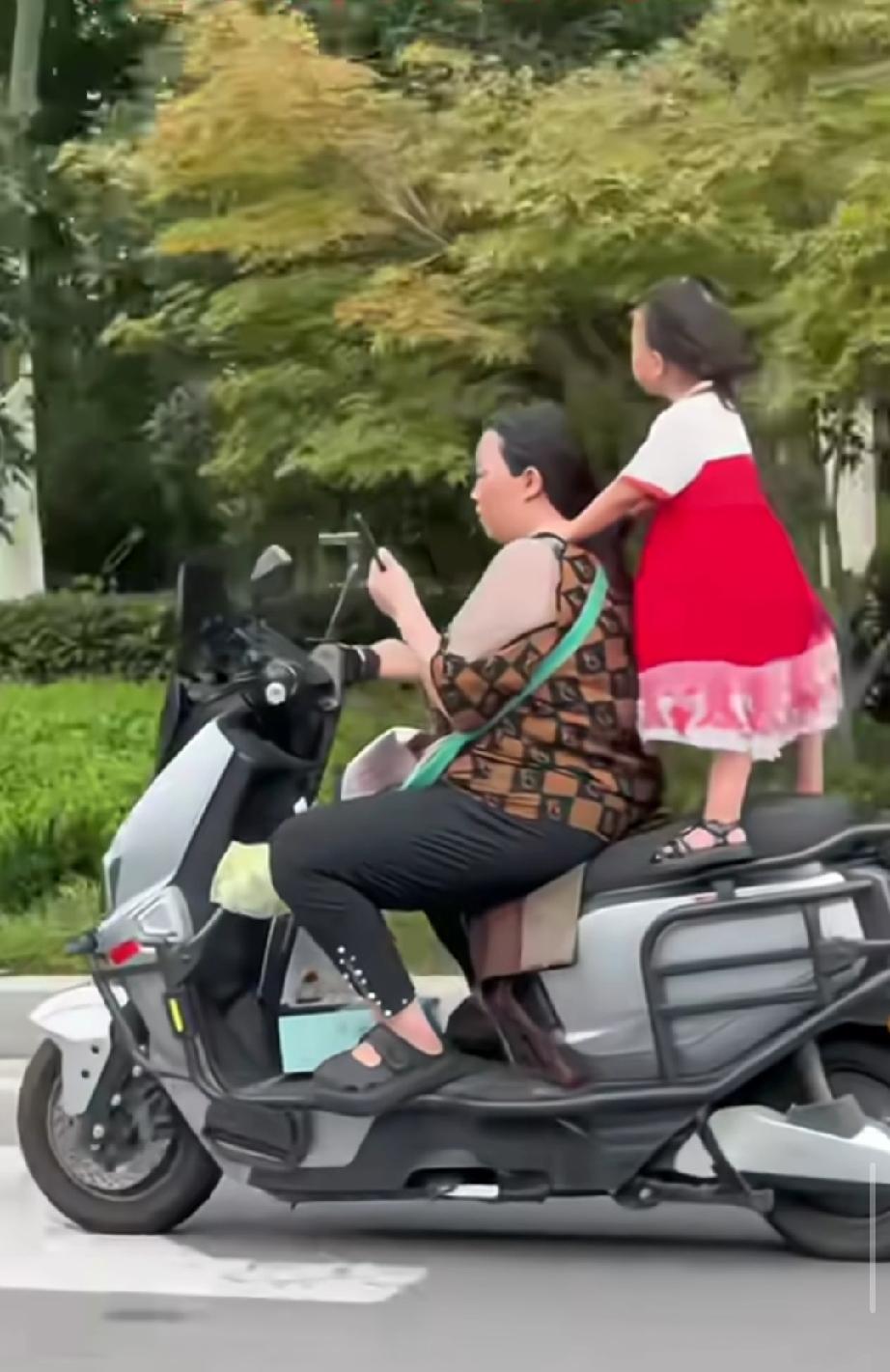瞧这娘俩，多么的英姿飒爽！路过的人都忍不住多瞅几眼。
妈妈骑着电瓶车，还不忘刷着