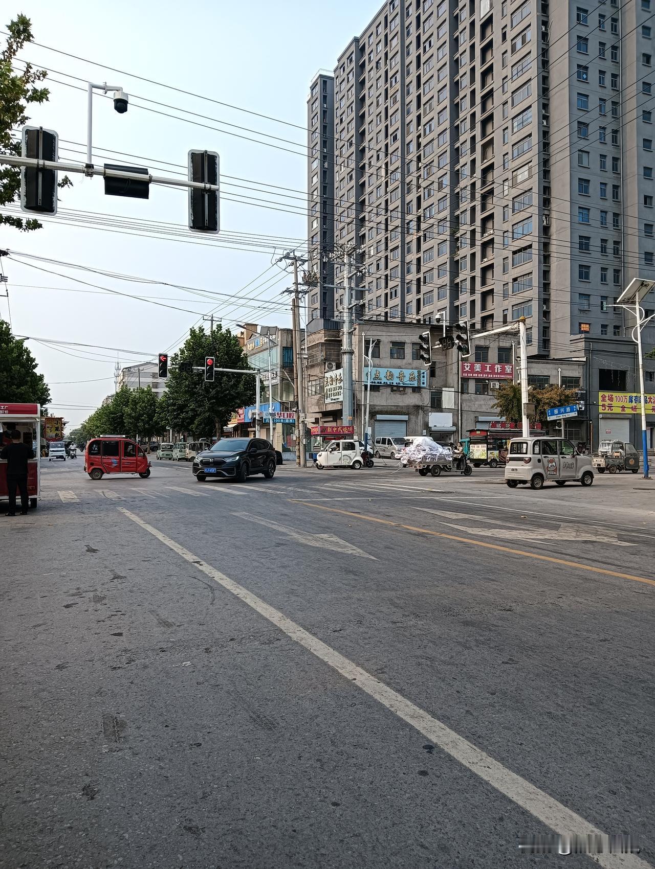 城市街道的早晨，车流缓慢，人影稀疏。