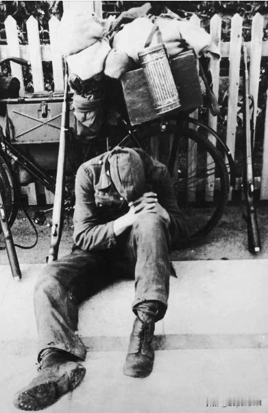 1945 年，一名疲惫不堪的德国士兵在战后漫长的回家途中在路边休息，后面有步枪很