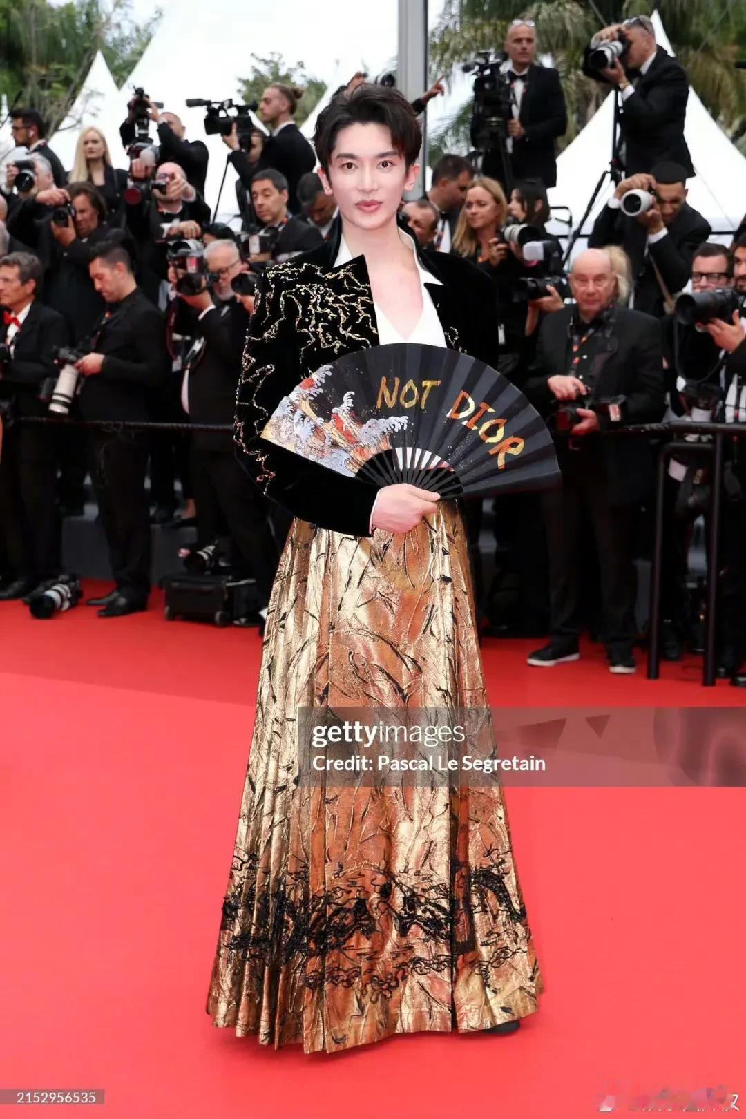 这哥们穿马面裙手拿折扇就这么走戛纳去了，折扇打开还写着：Not Dior，Fro