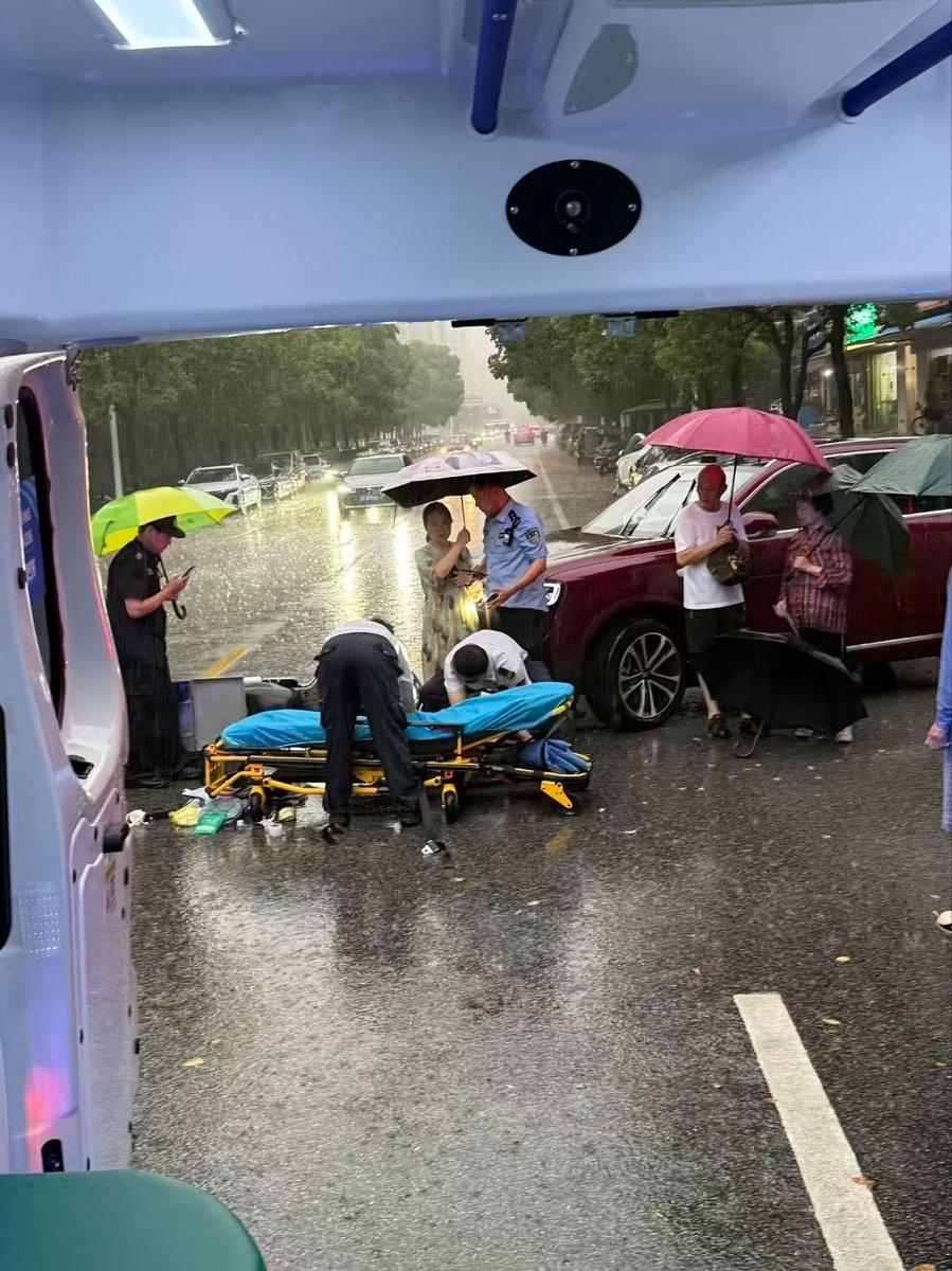 暴雨冲刷的街道，医护人员跪在泥泞积水之中施救。
浑身被大雨浸透，一心只顾及眼前亟