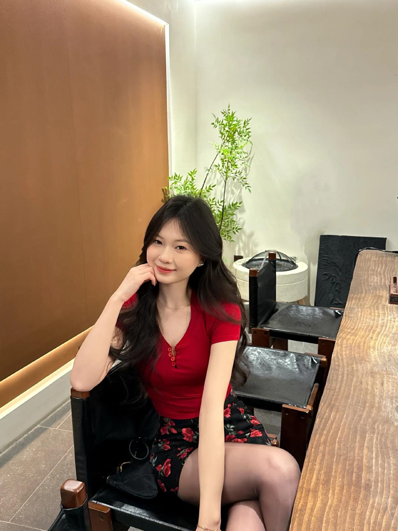 红色V领短袖T恤，搭配深色底玫瑰印花短裙，踩上一双黑色尖头高跟鞋，把甜辣感和纯欲