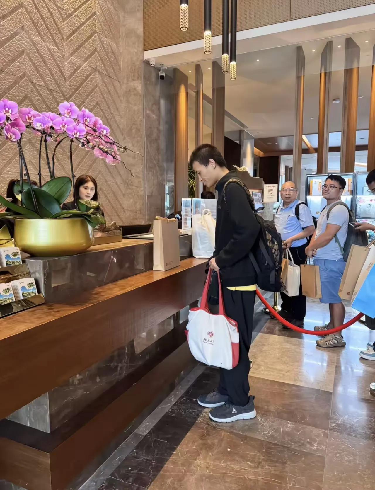 35岁韦东奕“韦神”在崇礼酒店大堂办理入住，背着大包参加数学活动，没有行李箱，拿