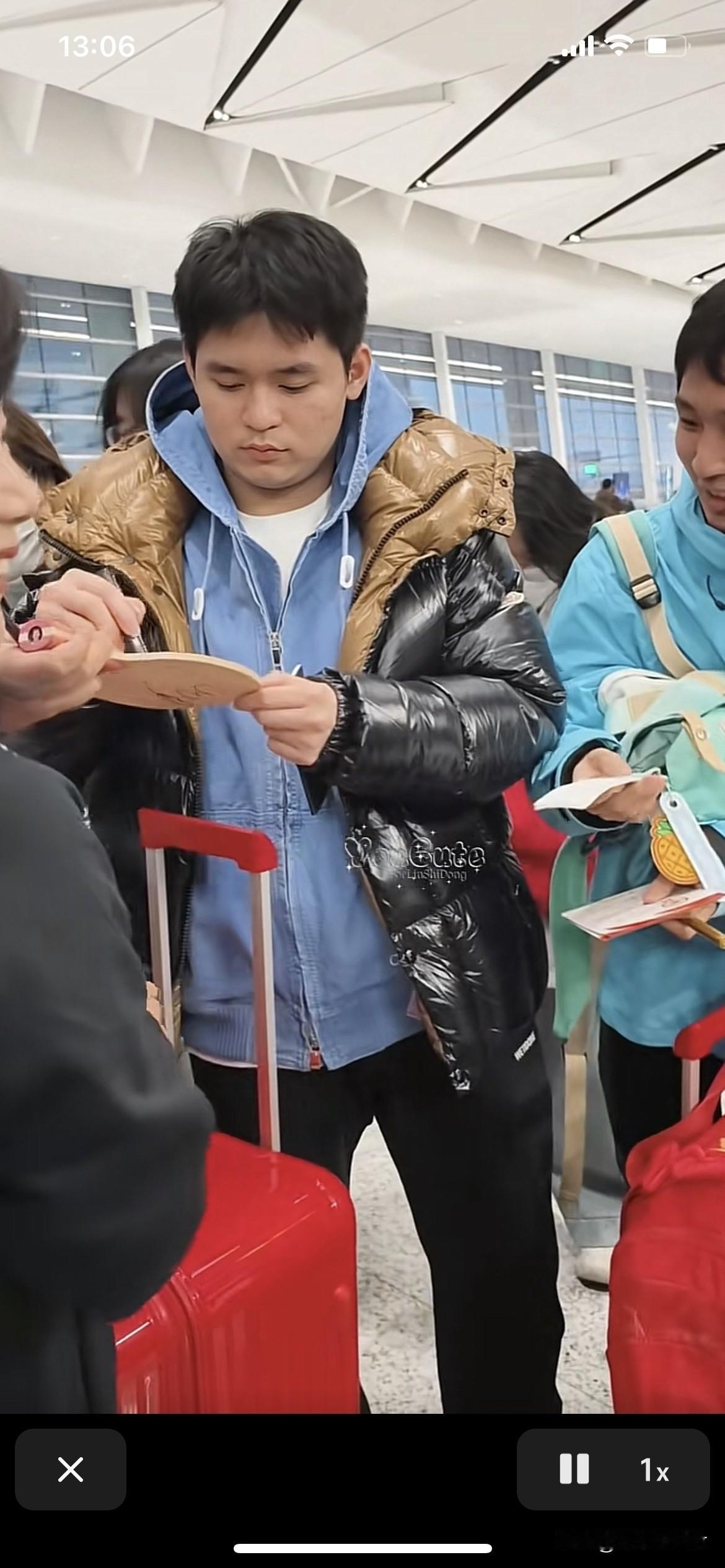 林诗栋在给女球迷签名，来了一个男粉丝穿蓝色外衣，拿起包包上的标签对林诗栋说：我也