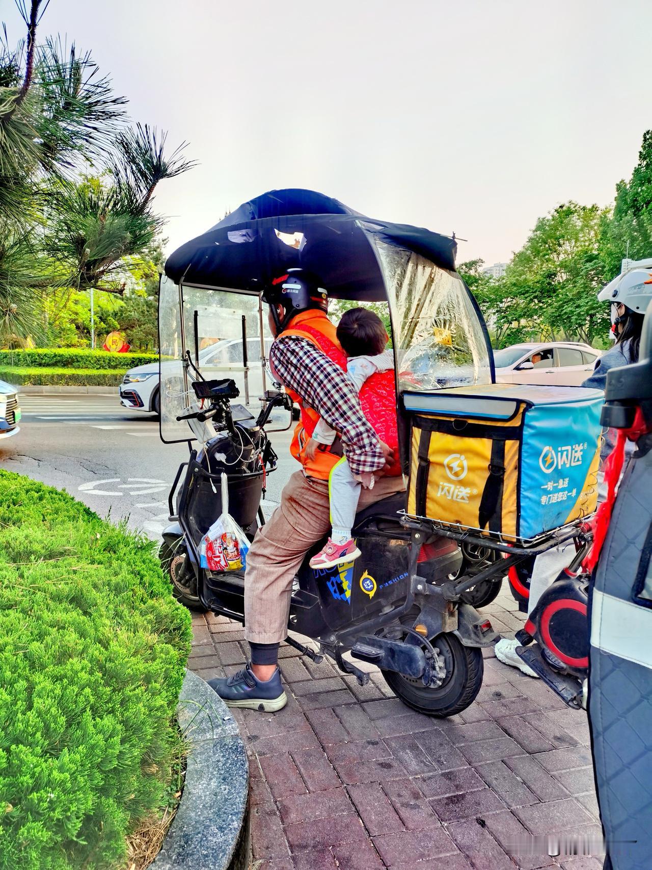 【奔波路上，济宁闪送员托举孩子，这一幕，藏着多少父亲的无奈？】在济宁城区的街头路