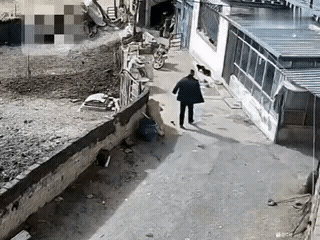 男子披着上衣回家，刚到家门口，一条大黑狗从身后悄无声息地跑向他对着男子的后腿肚就