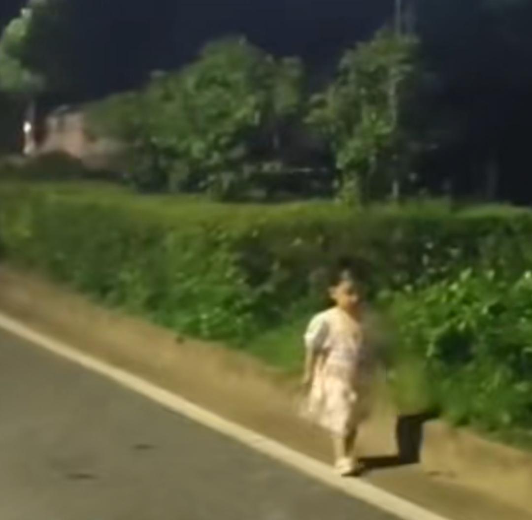 夜色深沉的江西街头，车流来来往往，一名年幼的小女孩独自走在马路边，嘴里不停念叨着