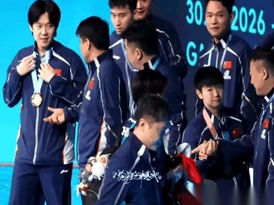 大合影，镜头前王楚钦举着金牌，镜头后，王皓指导的嘴就没停过，死死盯着他。
照片刚