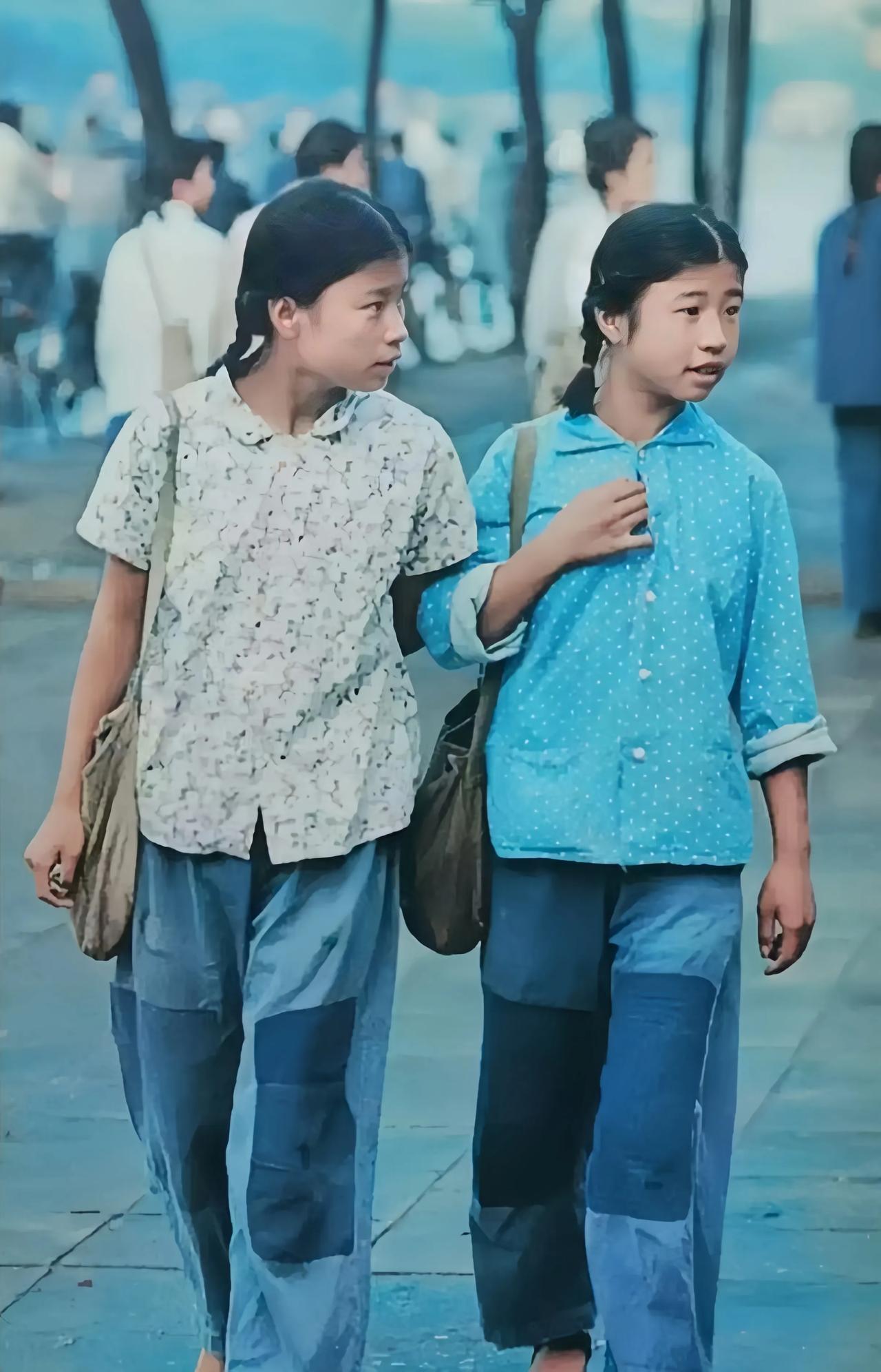 70年代，两个穿着普通的姑娘走在大街上。
只见她们裤子上打着两个大补丁，扎着两个