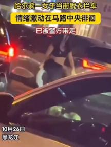 哈尔滨，10月26日，一名女子在街道中央突然开始脱去衣物，脱得全身只剩黑色内衣和