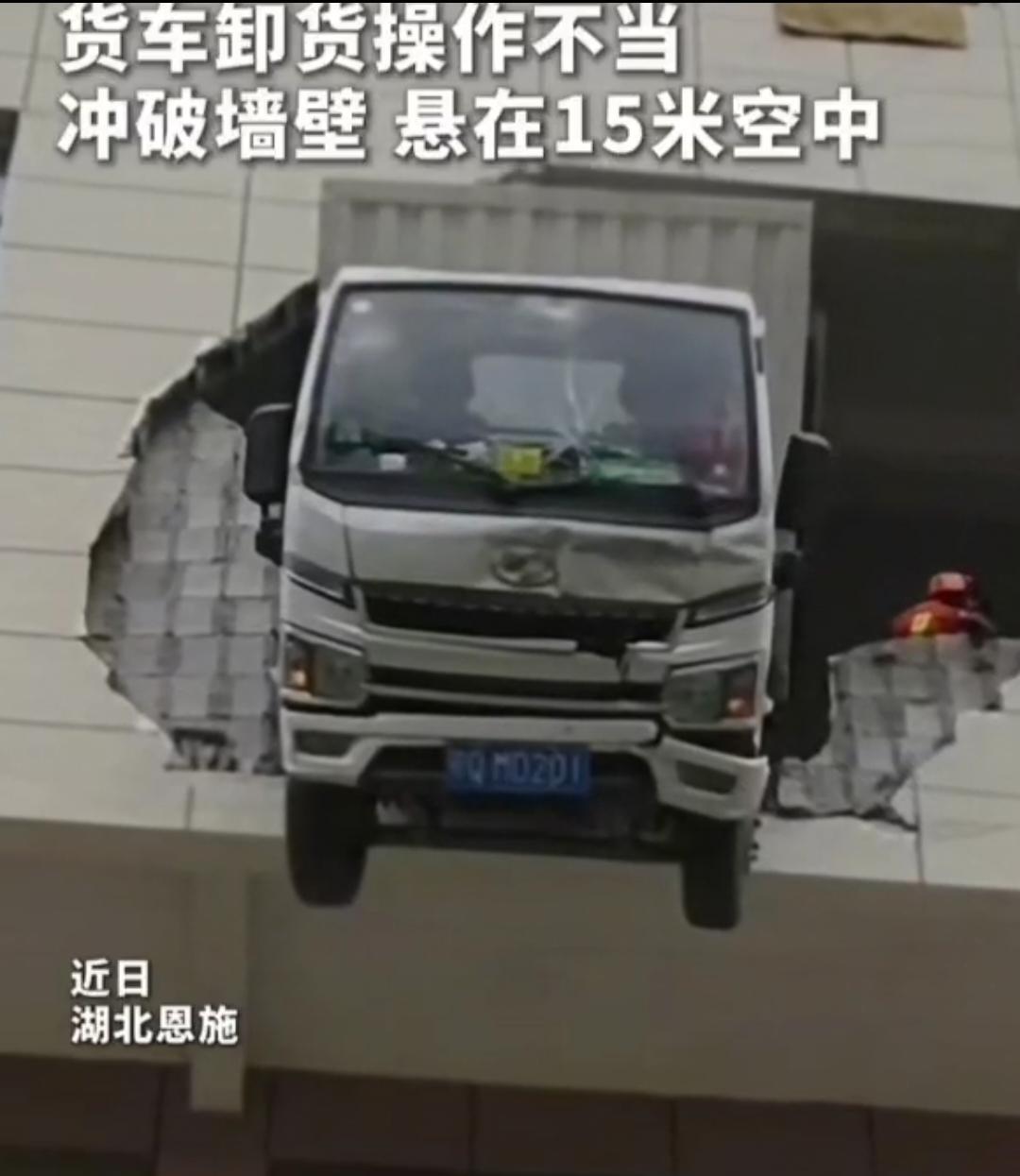 近日，湖北恩施，一货车司机在卸货时操作不当，车辆冲破库房墙壁，悬在15米高的空中