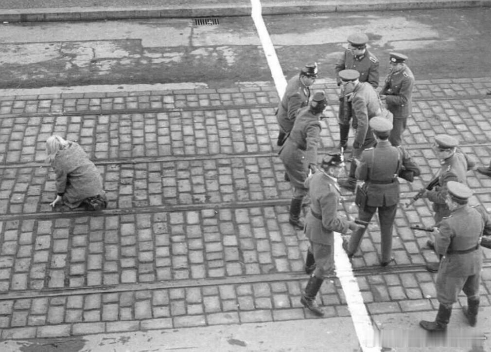 1955年，一名东德女孩刚刚冲过边界摔倒在地，三名西德警察手拉手试图阻止一队端着