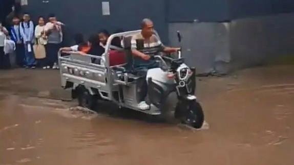 【河北一爷爷去接孙子，结果三轮车塞满了一车娃】
下雨天，河北某地路面积水，几个小