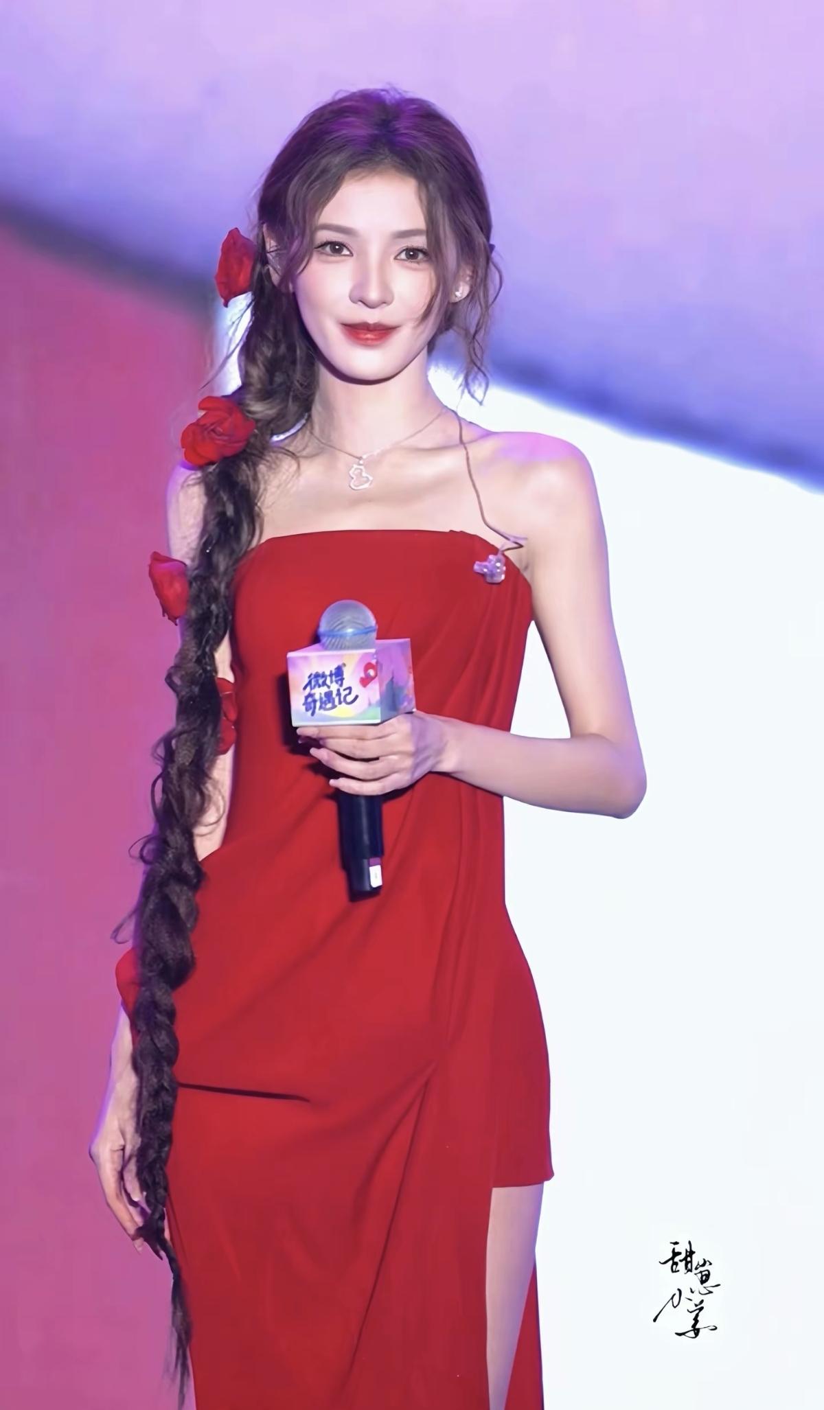 她身穿一袭斜裁红裙，点缀着立体玫瑰，搭配一条超长麻花辫，宛如从油画中走出的