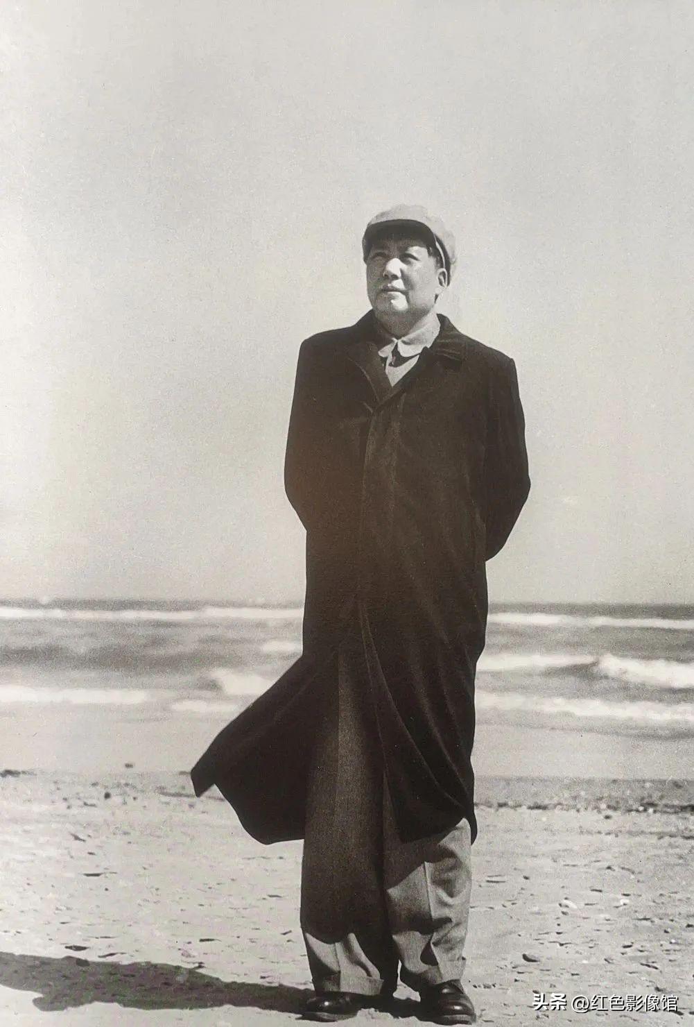 毛主席笔直伫立，双手背于身后，身姿挺拔沉稳。长风衣被海风扬起，身姿岿然不动，面朝