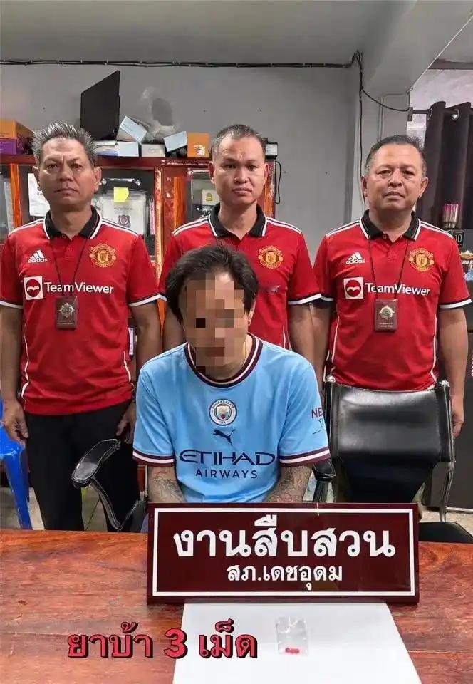 【泰国一名曼城球迷被捕，警方晒照穿曼联球衣和他合影】据《太阳报》报道，一名曼城球