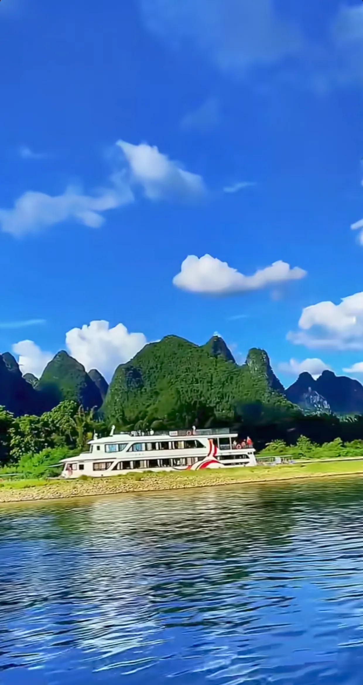 澄澈蓝天与碧绿江水相映成趣，奇峰矗立如画卷。游船缓缓划行，荡漾出诗意的涟漪。这里