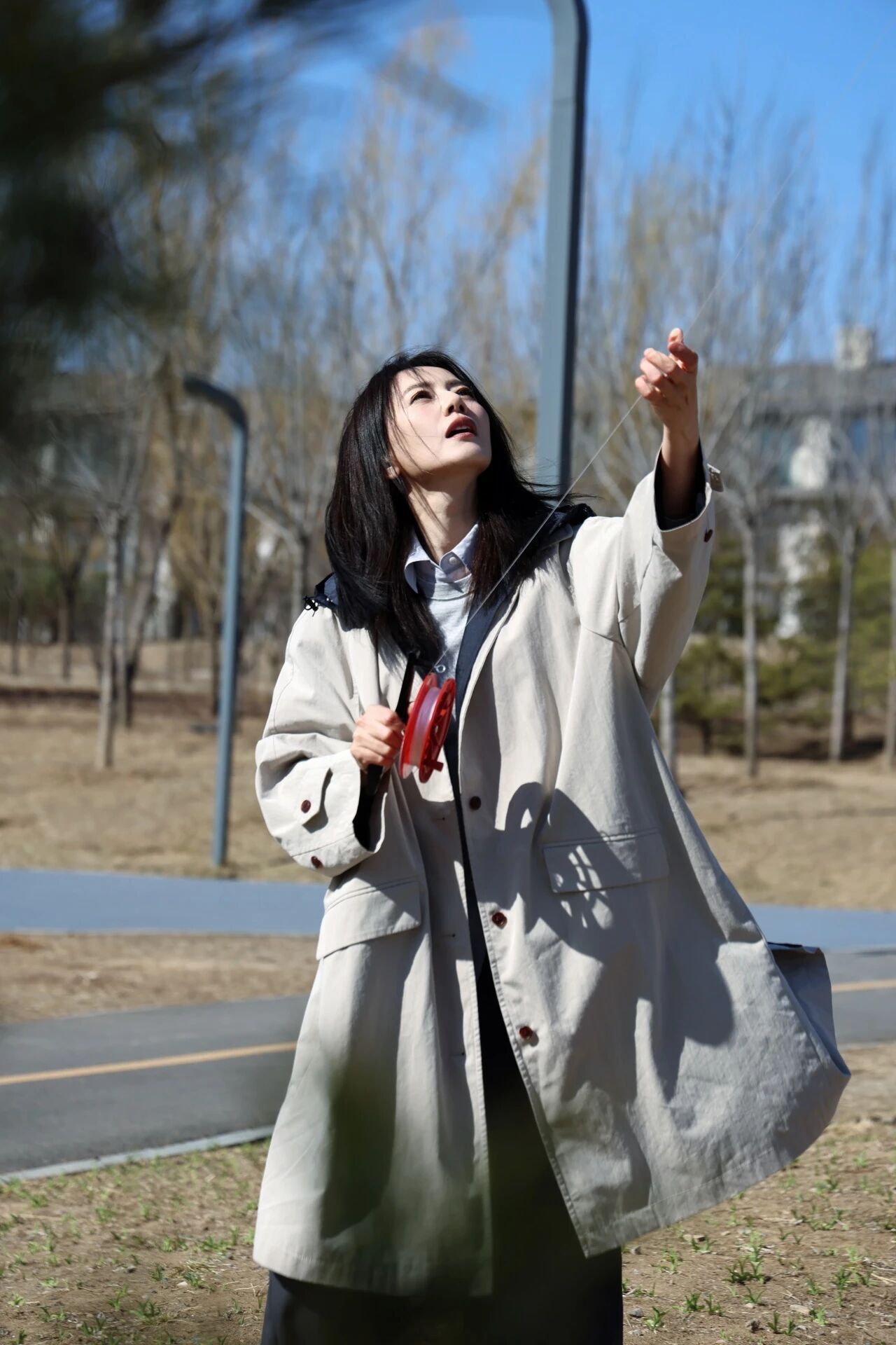 高圆圆  春风拂过郊野，风筝线牵起满格欢喜。身着浅卡其风衣，在晴日里整理线轴、举