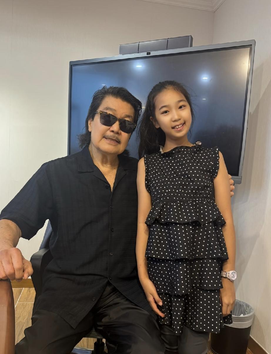 7月6日，赵雅芝老公黄锦燊在香港与钢琴小天才合影，黄锦燊戴了墨镜，头发眉毛胡子全