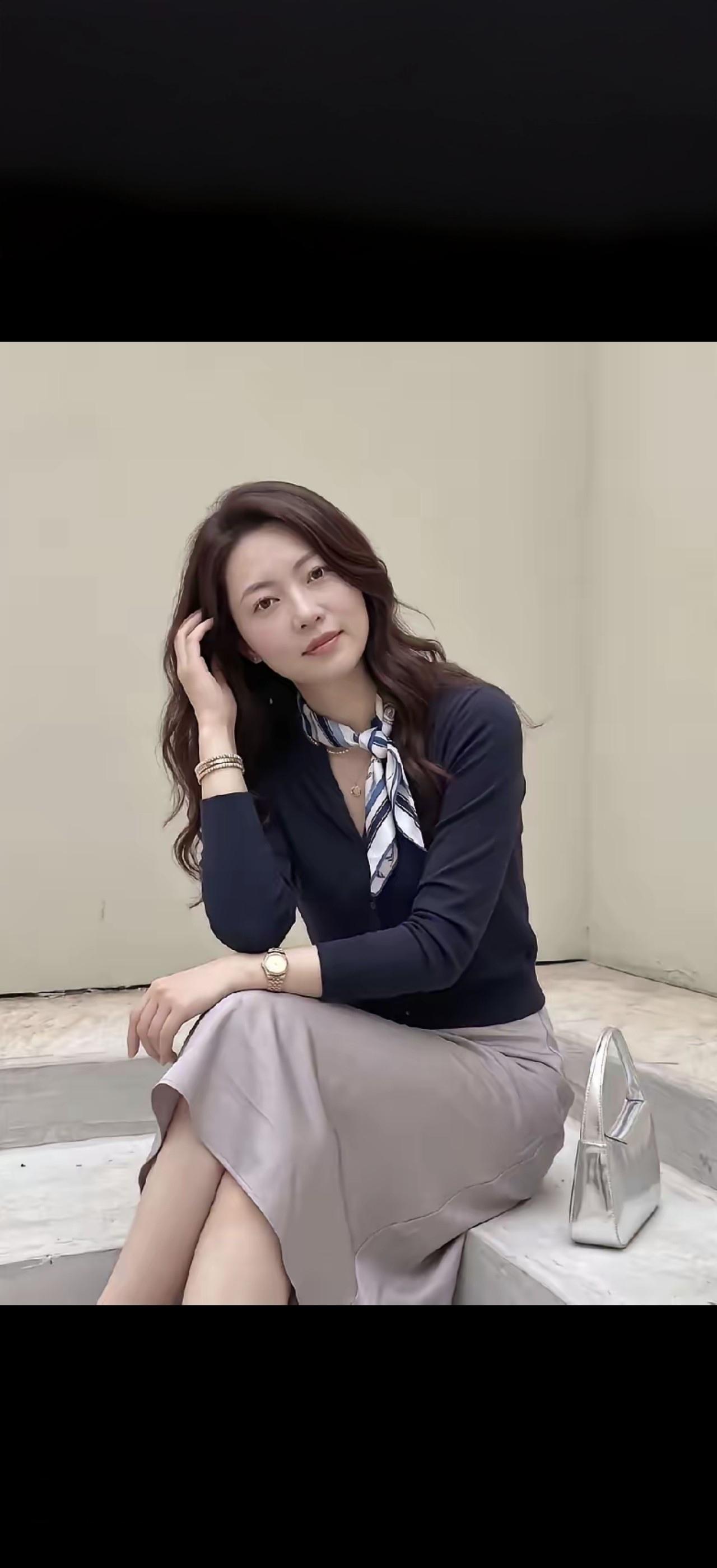 这位女士坐在台阶上，手托着头发，旁边放着一个手包。