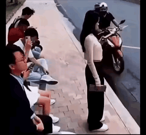 马来西亚公交站，女子低头刷手机，手里还攥着钱包，身后眼镜男突然起身，身前也窜出个
