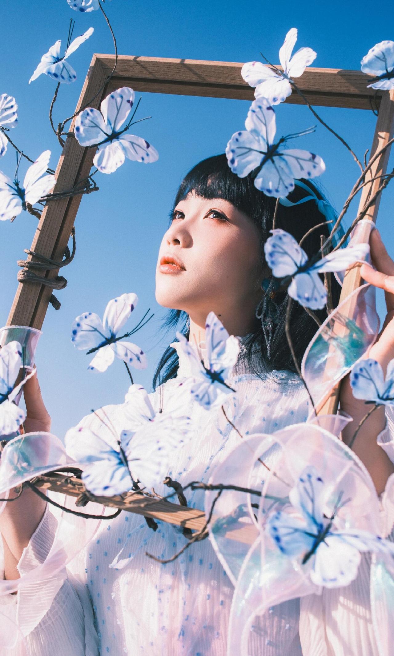 该画面以中景构图展现人物与道具的整体融合，人物双手环抱相框的姿态，让道具成为身体