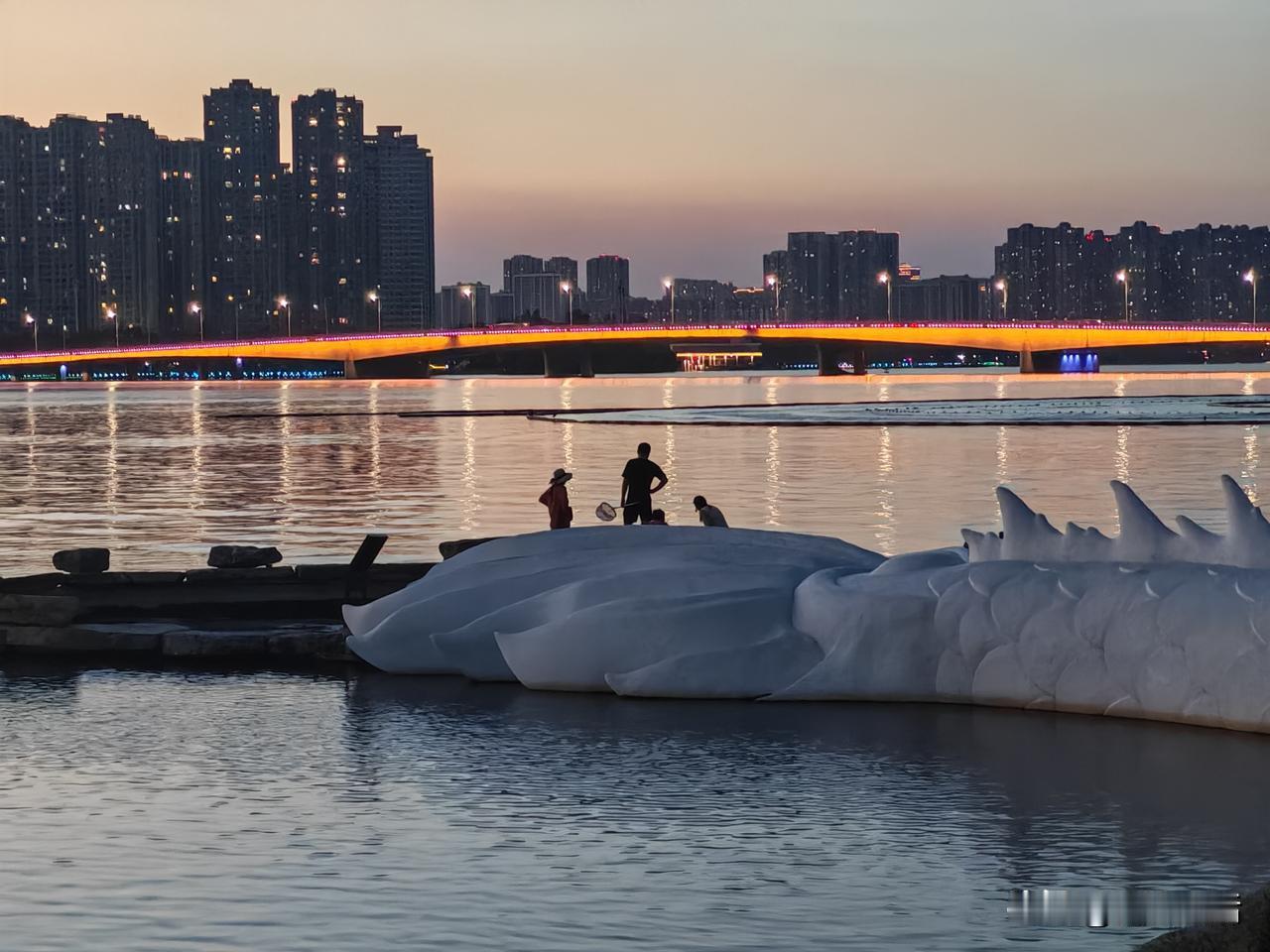 周末，龙子湖东公园龙鳞叠水景点，傍晚日落后人影绰绰，仍有不少市民游客在湖边游玩。